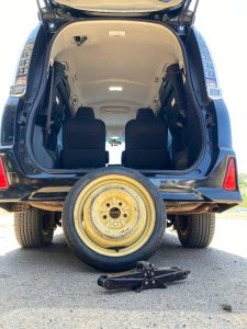 Doughnut Spare tire against the trunk of a Cabiz rental (Voxy) vehicle